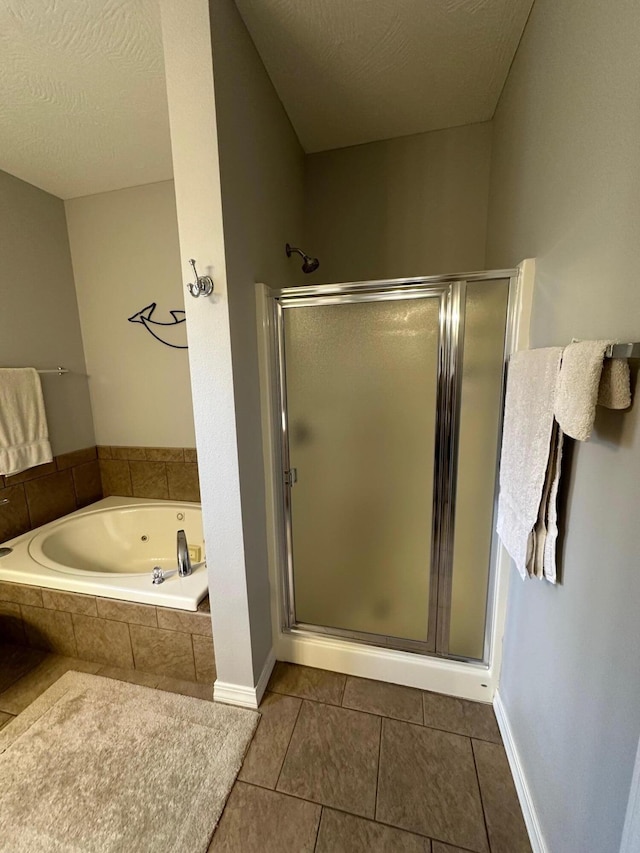 bathroom with tile patterned flooring, a stall shower, a bath, and a textured ceiling