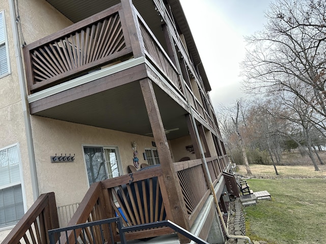 view of exterior entry with a yard, stucco siding, and a balcony