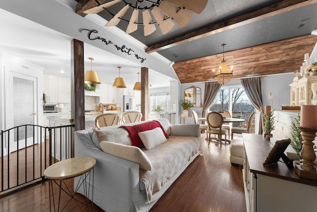 living area featuring beam ceiling, dark wood-type flooring, and ceiling fan