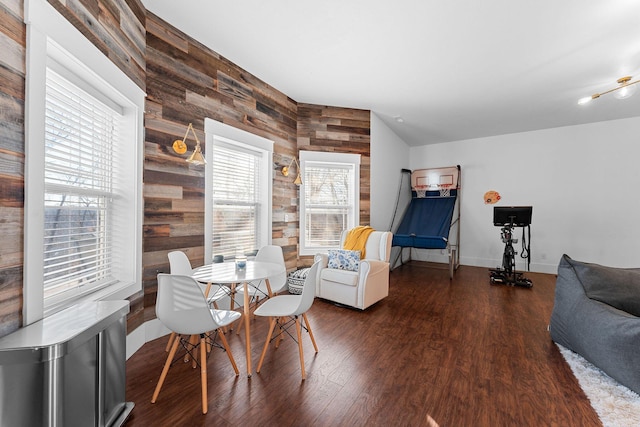 dining area featuring wood walls, baseboards, and wood finished floors