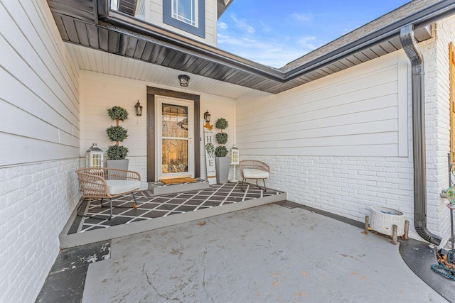 view of exterior entry with brick siding and a porch