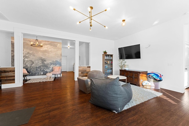 living area featuring a notable chandelier, wood finished floors, visible vents, and baseboards