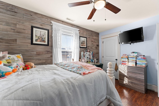 bedroom featuring visible vents, a ceiling fan, wood finished floors, baseboards, and an accent wall