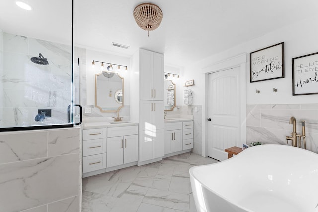 bathroom with visible vents, marble finish floor, two vanities, a sink, and a soaking tub