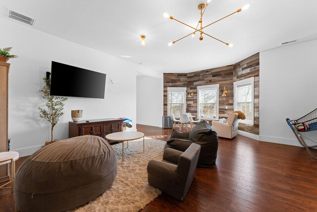 living room featuring wood finished floors, visible vents, a chandelier, and baseboards