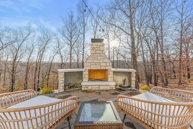 view of patio featuring a forest view and an outdoor stone fireplace