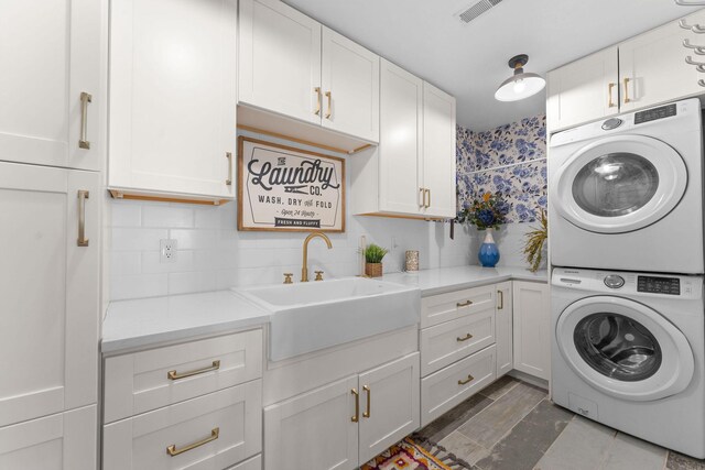 laundry room featuring stacked washer / dryer, cabinet space, visible vents, and a sink