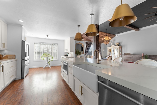 kitchen with dark wood finished floors, white cabinetry, stainless steel appliances, light countertops, and hanging light fixtures