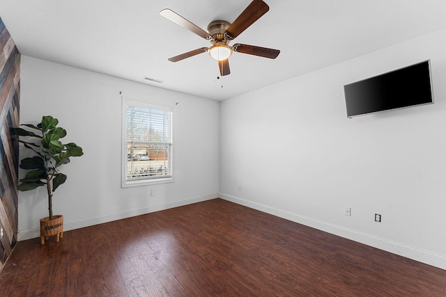 spare room featuring visible vents, ceiling fan, baseboards, and wood finished floors