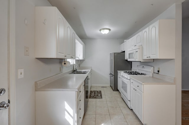 kitchen with baseboards, light countertops, light tile patterned flooring, white appliances, and white cabinetry