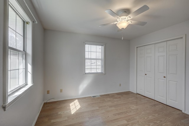 unfurnished bedroom with visible vents, light wood-style flooring, a closet, baseboards, and ceiling fan