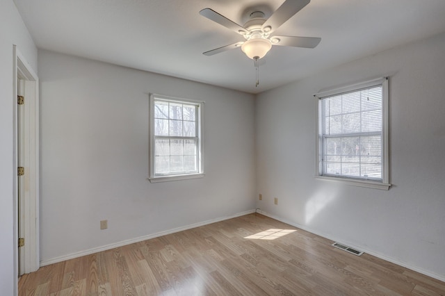 spare room with light wood finished floors, visible vents, ceiling fan, and baseboards