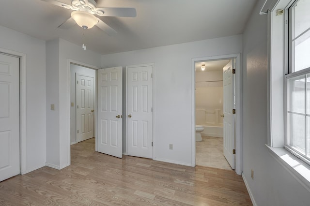 unfurnished bedroom featuring baseboards, light wood-style floors, and ensuite bath