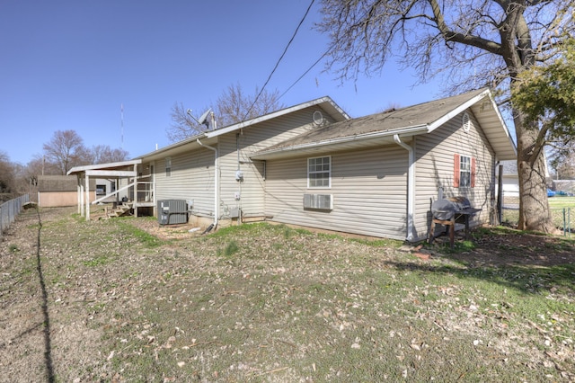 rear view of house featuring central air condition unit and fence