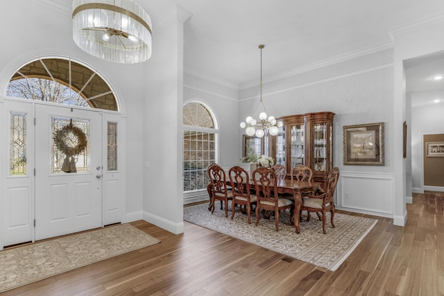 foyer entrance featuring a notable chandelier, crown molding, baseboards, and wood finished floors