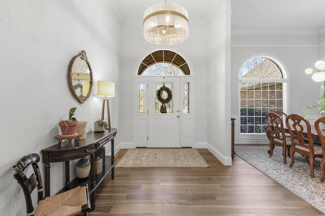 entryway featuring baseboards, wood finished floors, a chandelier, and crown molding