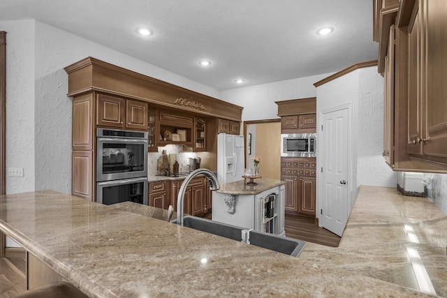 kitchen featuring a sink, appliances with stainless steel finishes, a textured wall, and open shelves