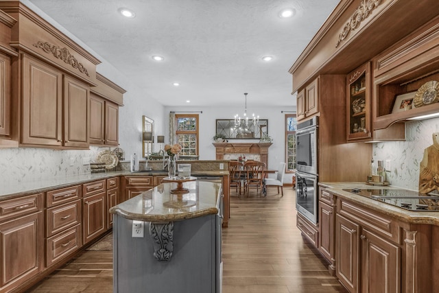 kitchen with brown cabinets, dark wood-type flooring, backsplash, appliances with stainless steel finishes, and stone counters