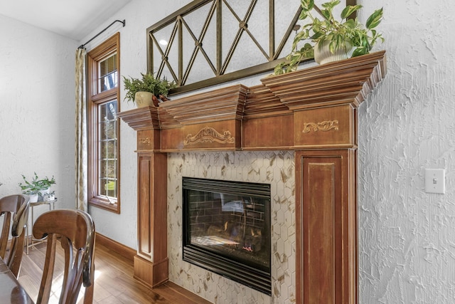 interior details with a high end fireplace, baseboards, a textured wall, and wood finished floors