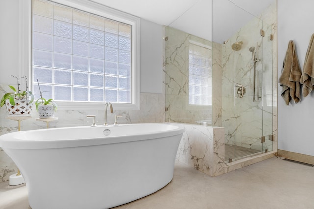 full bath featuring a marble finish shower, visible vents, a freestanding bath, and tile walls