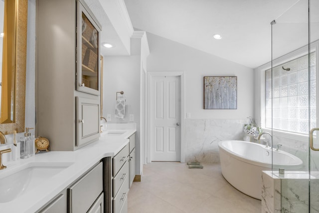 bathroom featuring double vanity, a freestanding tub, lofted ceiling, and a sink