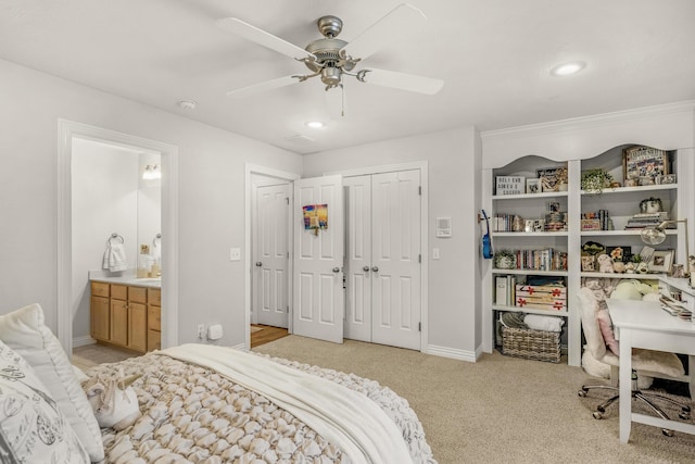 bedroom with baseboards, ceiling fan, light colored carpet, ensuite bathroom, and a closet