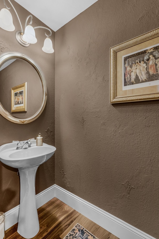 bathroom with a sink, baseboards, wood finished floors, and a textured wall