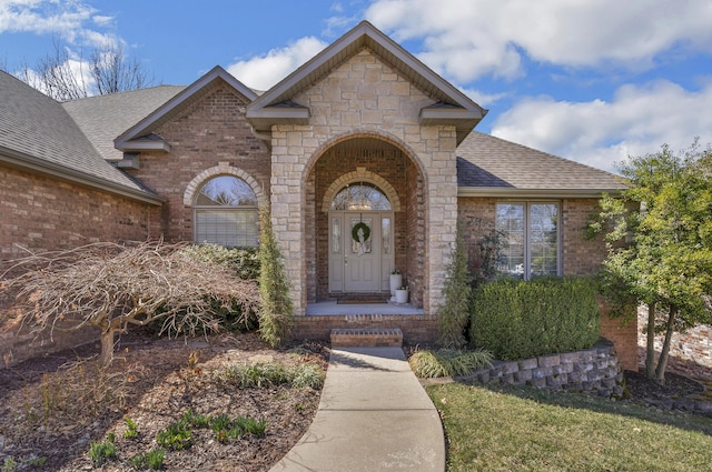 property entrance featuring brick siding and roof with shingles