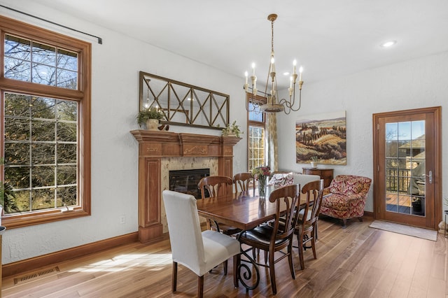 dining area with visible vents, baseboards, a fireplace, and light wood finished floors