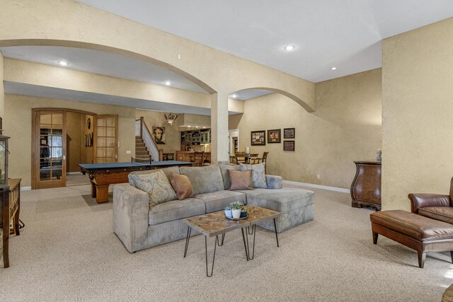 living room with light carpet, stairway, baseboards, and a textured wall