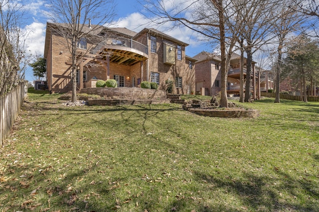 back of property with a yard, fence, and brick siding