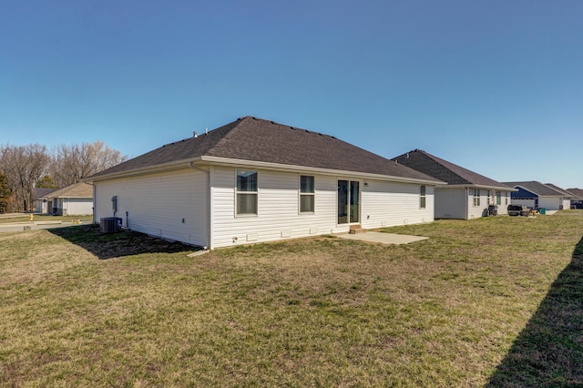 rear view of house featuring a lawn, cooling unit, a shingled roof, and a patio