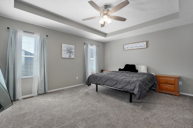 bedroom with a tray ceiling, baseboards, a ceiling fan, and carpet flooring