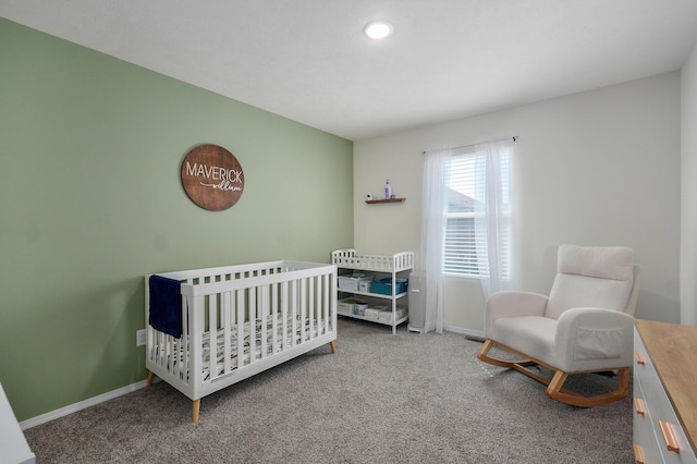 bedroom with a nursery area, baseboards, and carpet