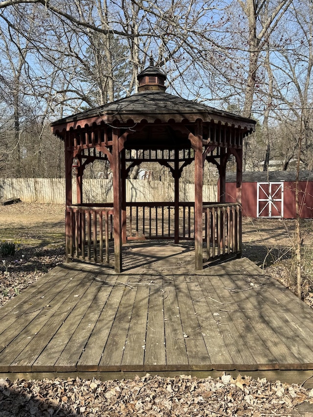 wooden terrace featuring a gazebo and an outbuilding