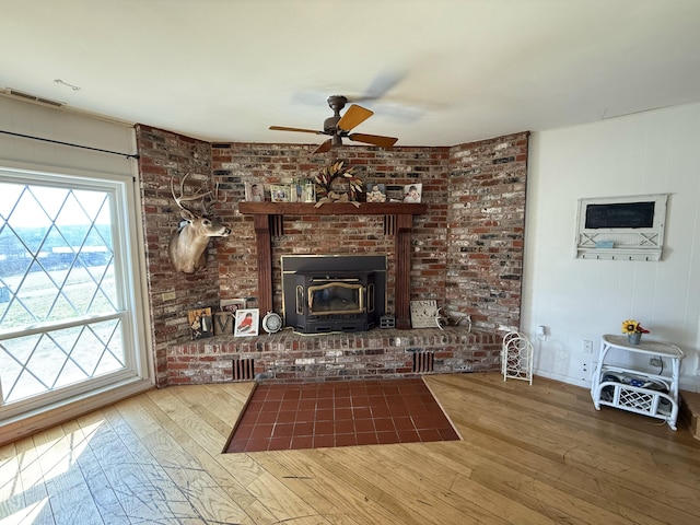 unfurnished living room featuring a ceiling fan, hardwood / wood-style floors, and a wood stove