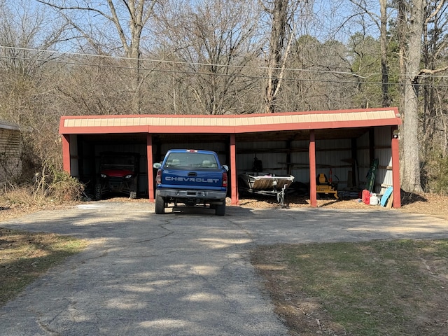 view of parking with a carport, driveway, and a pole building