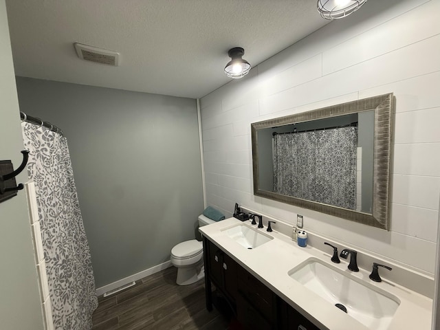 full bathroom featuring a textured ceiling, wood finished floors, visible vents, and a sink