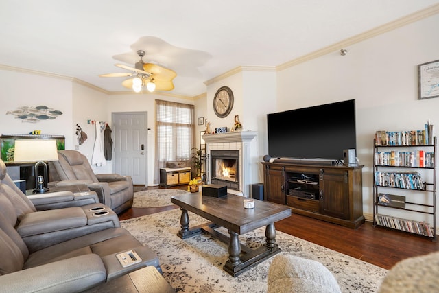 living area with a fireplace, crown molding, dark wood-style floors, and a ceiling fan