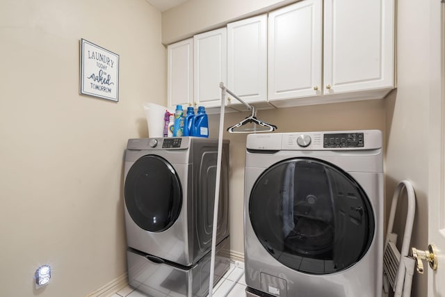 clothes washing area featuring light tile patterned floors, cabinet space, baseboards, and washer and clothes dryer