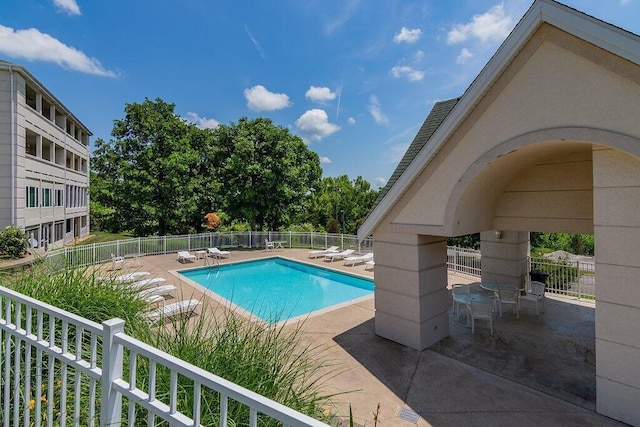 community pool with fence and a patio area