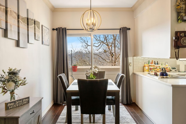 dining area featuring a chandelier, ornamental molding, baseboards, and dark wood-style flooring