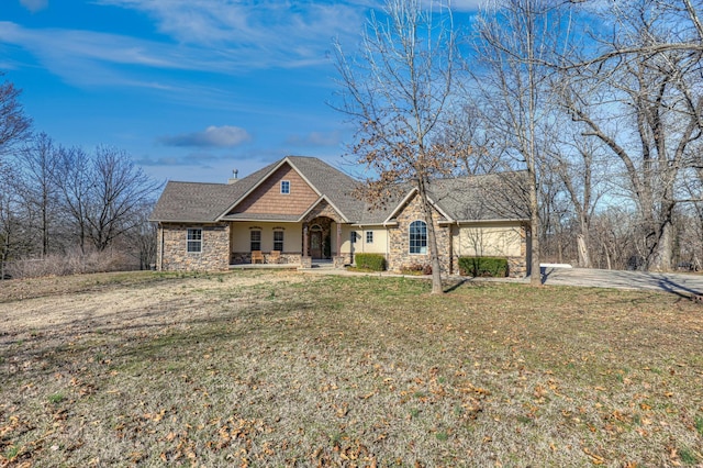 craftsman house featuring stone siding, driveway, and a front lawn