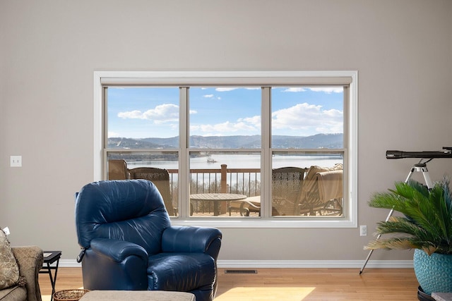 living area featuring visible vents, baseboards, a water and mountain view, and wood finished floors