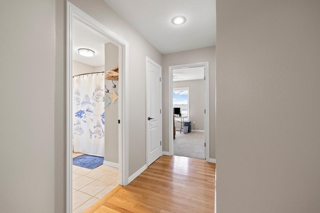 corridor featuring light wood-style flooring and baseboards