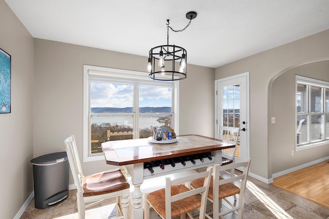 dining space with an inviting chandelier, baseboards, and arched walkways