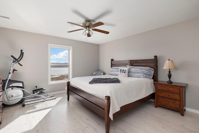 bedroom with light wood finished floors, visible vents, ceiling fan, and baseboards