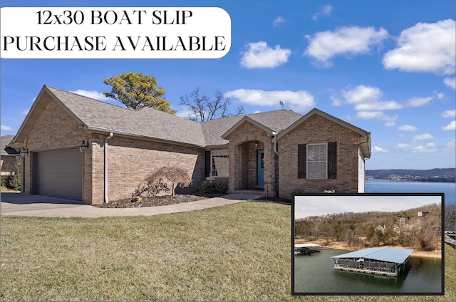 view of front of house featuring a front yard, driveway, a garage, a water view, and brick siding