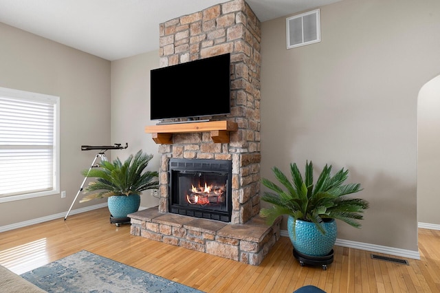 living area with visible vents, a fireplace, baseboards, and hardwood / wood-style flooring