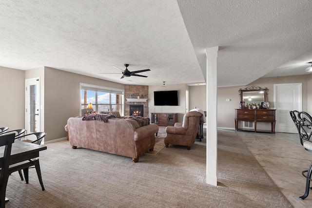 living room with a stone fireplace, a textured ceiling, baseboards, and ceiling fan